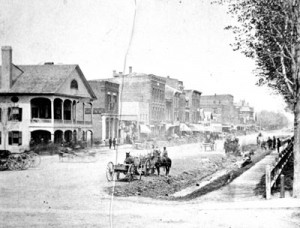 The Franklin County Bank is seen in this photo looking north up Main Street from Fairfield Street. The bank is the building with the rectangular sign on its side. The building to its left, with the elaborate porches, is the American House. It was on the sidewalk in front of it that Bennett Young signaled the start of the raid. At right is the park where residents were held hostage