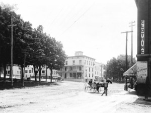 The First National Bank is visible in the distance on Fairfield Street. It is just behind where the men are seated on the bench in the park.