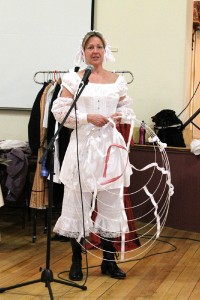 Lynn Sawyer, stripped down to just her undergarments and corset, shows the audience how to put on a hoop skirt. The skirts helped achieve the era’s desired hourglass figure, as did dropped shoulders and oversize sleeves.