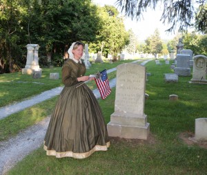Lynn Sawyer places a marker and flag on the grave of James A. Chamberlin.