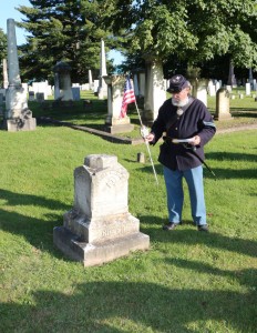 Jim Fouts places a marker and flag on the grave of Luther A. Greene.