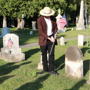 Bob Bushnell places a marker and flag on the grave of William W. Garvin.